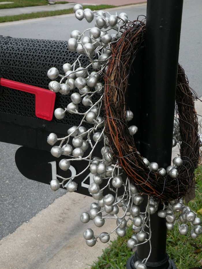 Grapevine Christmas wreath on a mailbox. Grapevine wreath on mail box post with silver berry garland wrapped around.