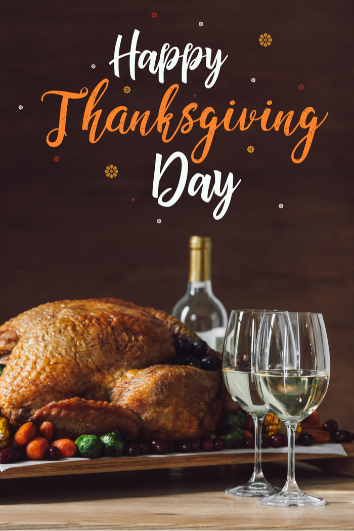 A happy Thanksgiving day quotes on a photo of a Thanksgiving turkey next to a bottle and two glasses of white wine.
