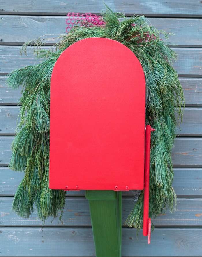 Decorated red mailbox Red mail box with pin boughs over the top.