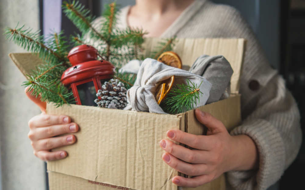 Decorating a mailbox for the holidays. Hands holding a box of supplies to decorate a mailbox.