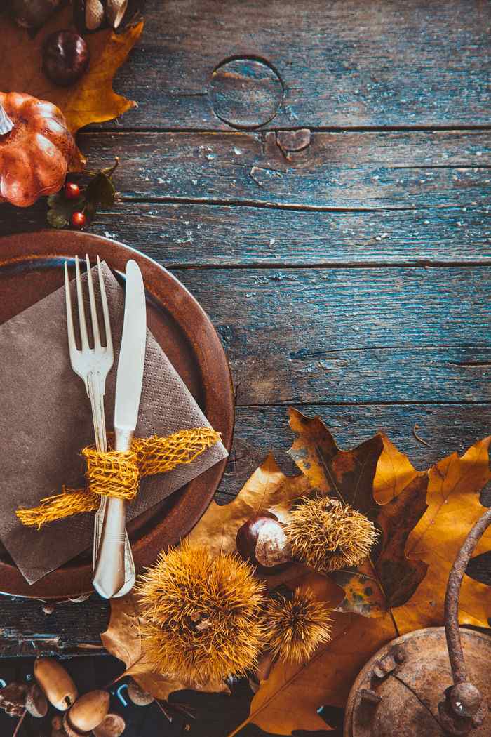 A Thanksgiving place setting and foliage on distressed wood.