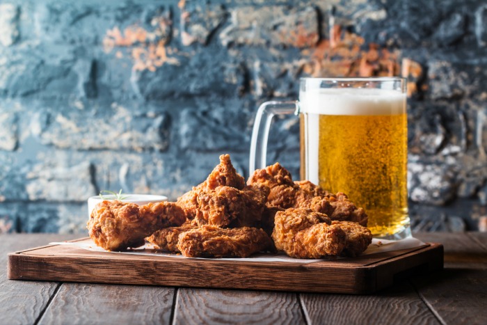 chicken wings and beer. Tray of chicken wings and mug of beer against a blue brick wall to celebrate Super Chicken Wing Day.