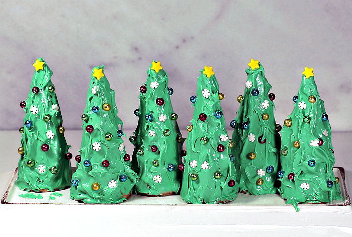 Making Christmas trees from waffle cones. Waffle cones decorated like Christmas trees on a plate.