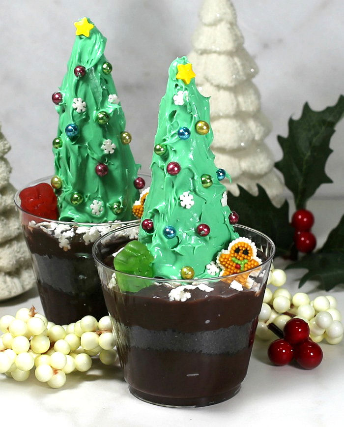 Finished Christmas trees. Chocolate dirt pudding using two waffle cones with green frosting, ornaments, gingerbread and snowman gummy.