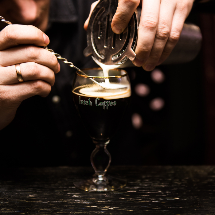 A bartender pouring an Irish coffee cocktail. A bartender pouring an Irish coffee cocktail.