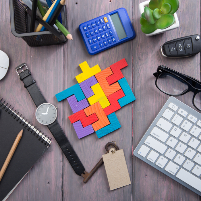 Wooden block puzzle and other various desk items on a desk. Wooden block puzzle on a work desk during National Puzzle Day.