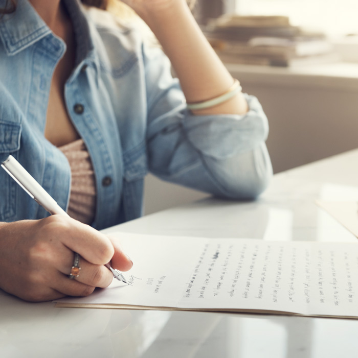Woman writing a handwritten letter for National Handwriting Day.