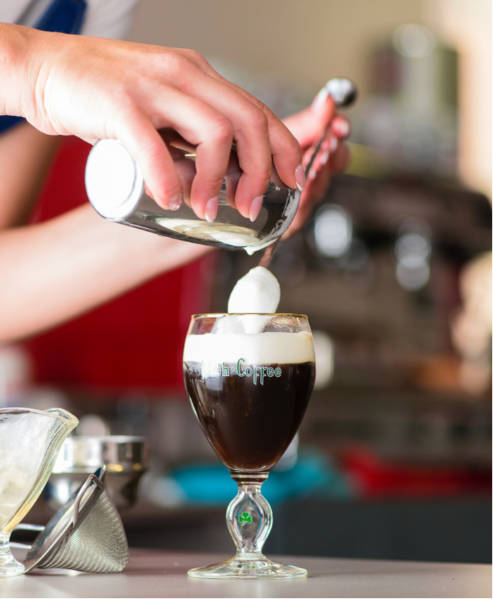 A bartender pouring cream onto an Irish coffee. A bartender pouring cream onto an Irish coffee to honor Irish coffee history.