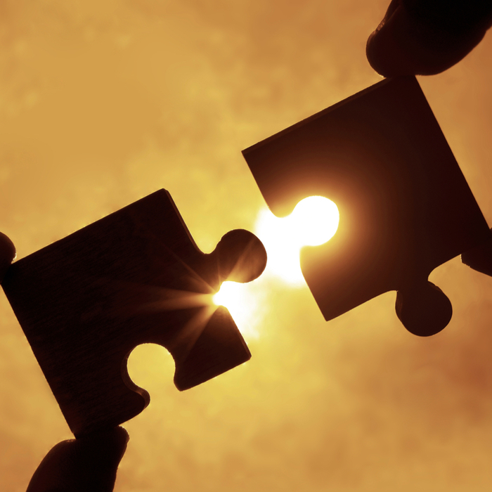 Putting together a puzzle by assembling the last two pieces in front of the sun.