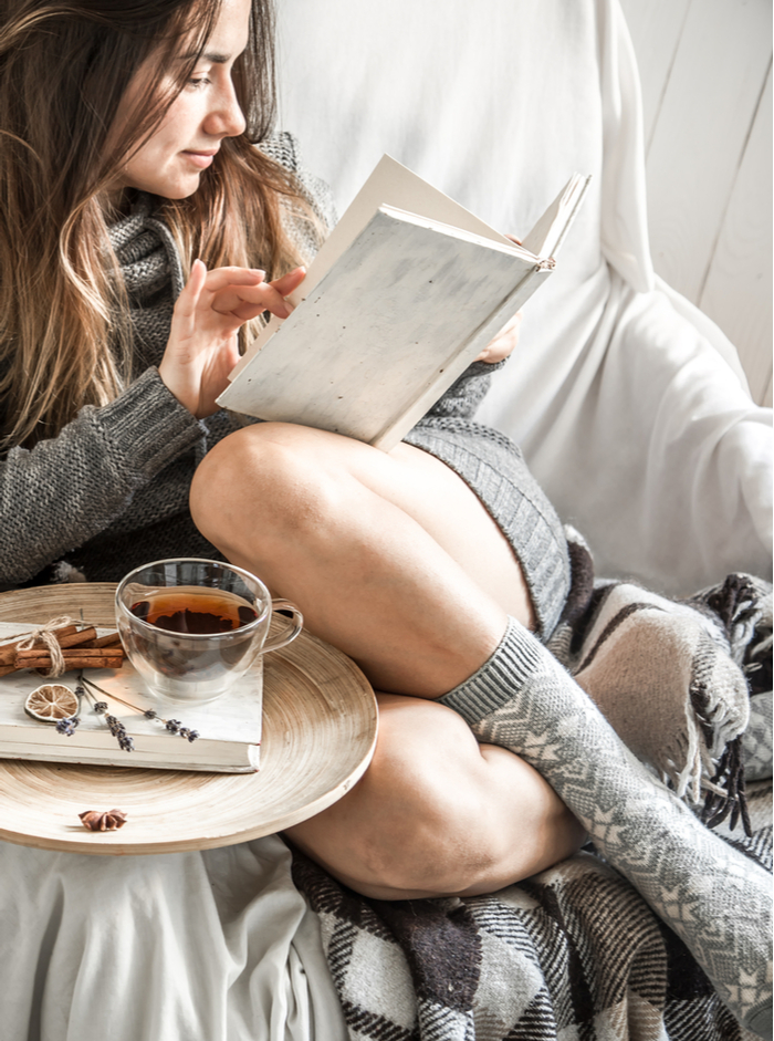 A woman practicing self care and reading as a reward to celebrate keeping New Year's resolutions.