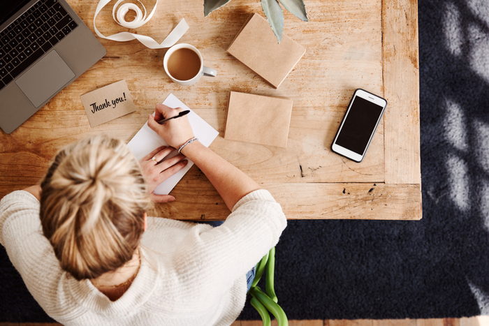 Woman writing a thank you note. Woman writing a handwritten thank you note at her desk for National Handwriting Day.