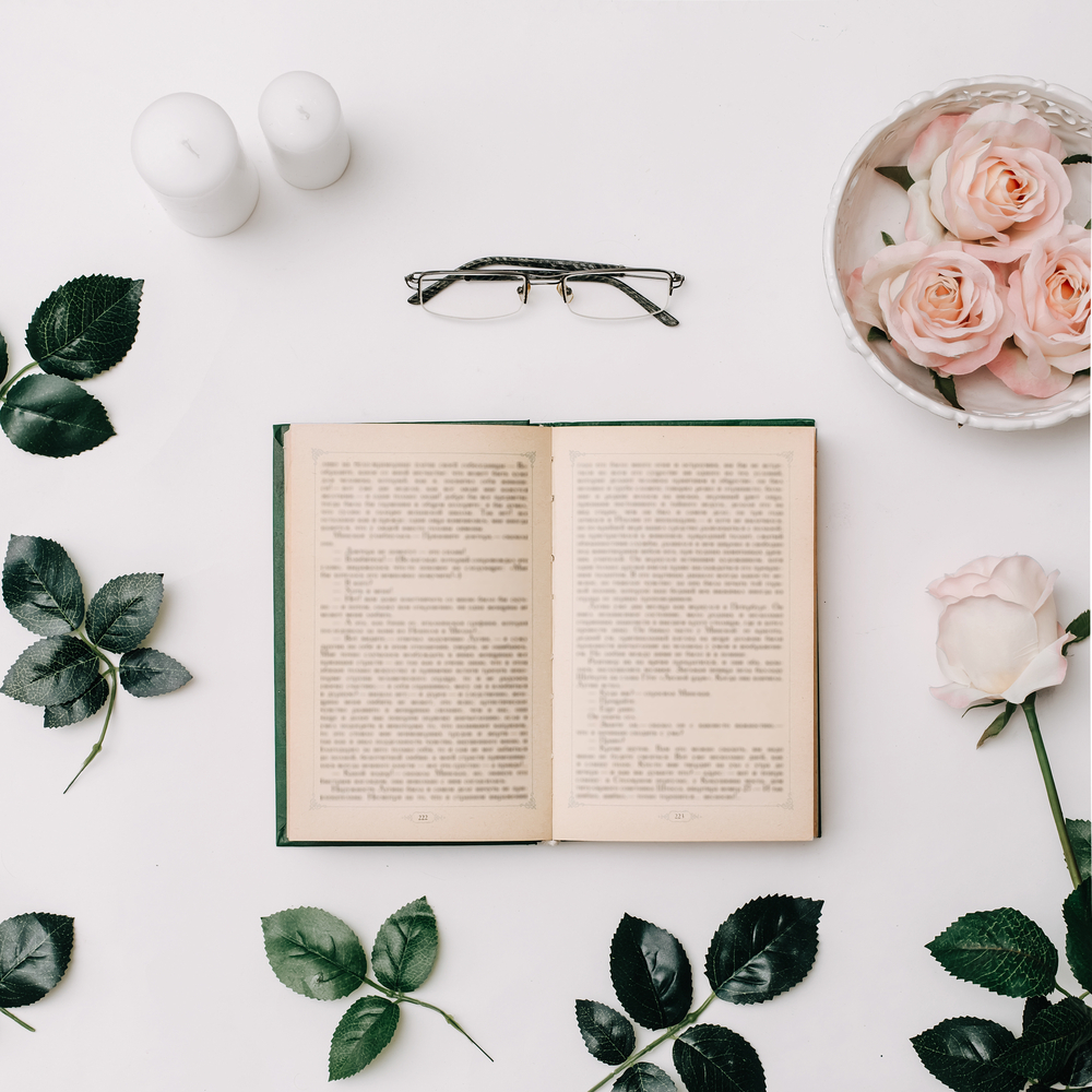 An open book on a white background with roses and two candles.