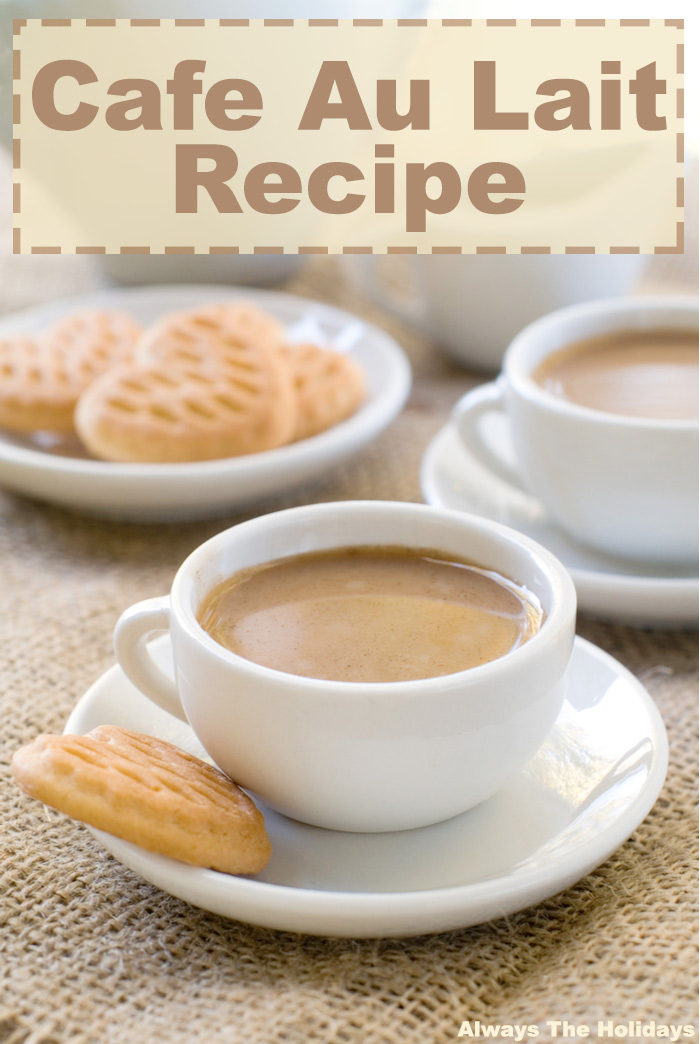 A cup with a cafe au lait in it, and a biscotti beside it on a saucer on a burlap cloth with a text overlay reading "cafe au lait recipe".