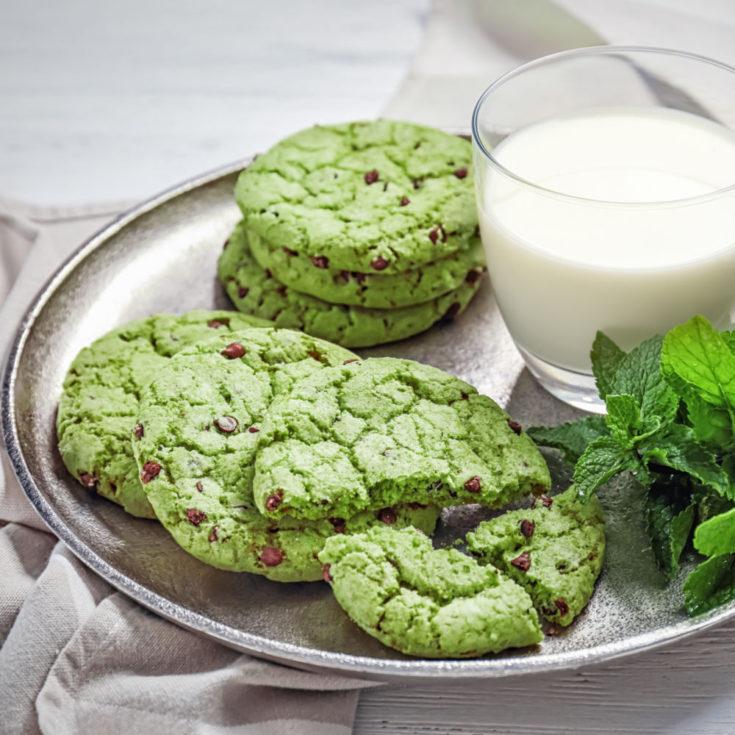 Mint chocolate chip cookies on a plate with a glass of mink.
