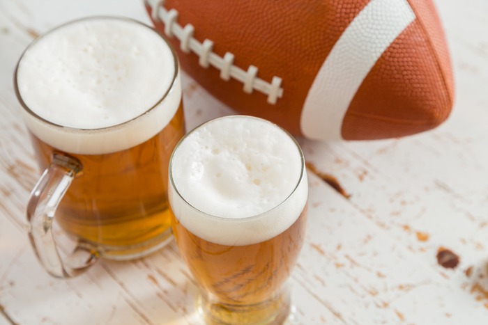 Football and two beers on a distressed wooden table. Football and two beers on a white distressed table on National Football Hangover Day.