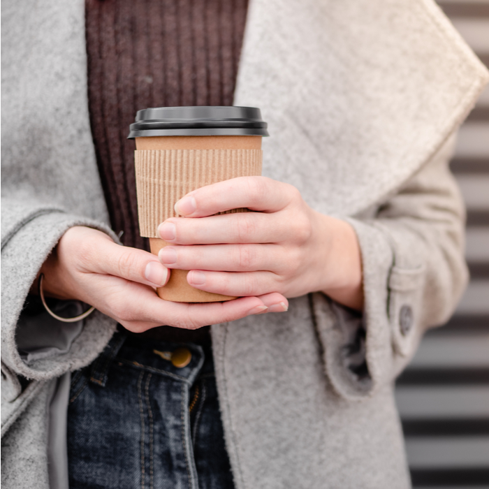 A woman holding a to go coffee cup after learning how to make a cafe au lait.
