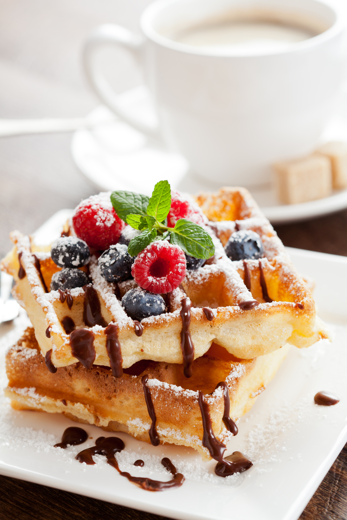 A stack of waffles in front of a latte to celebrate Galentine's Day.