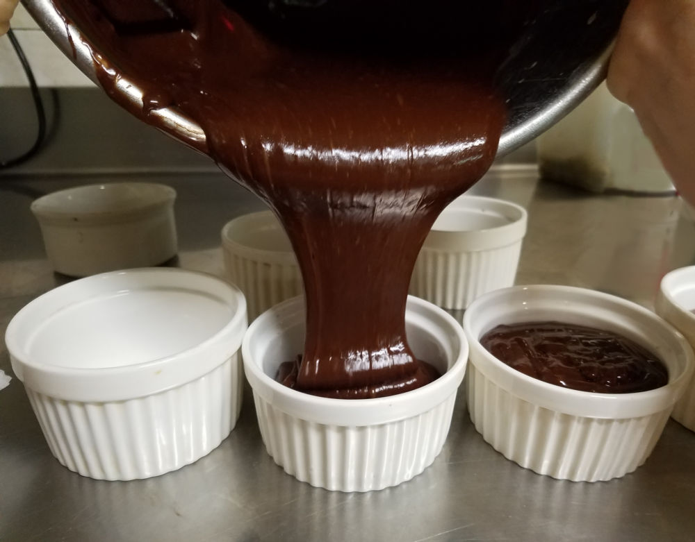 Pouring chocolate mixture into ramekins.