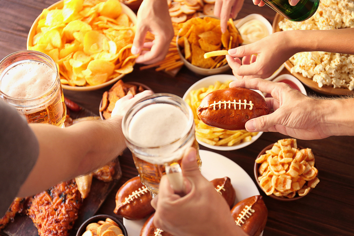 Super Bowl party food. Hands holding beer and digging into appetizers for a party about football.