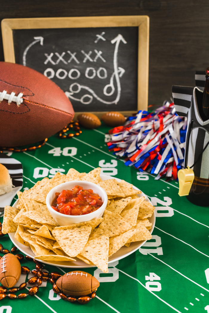 Football Sunday table with food and props. a table with a chalk board, football, and snacks on it.