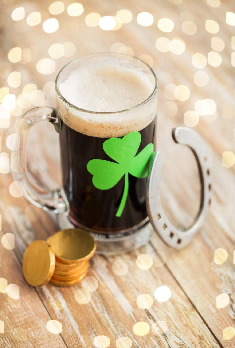 Luck of the Irish! A mug of beer, a horse shoe and gold coins to celebrate St. Patrick's Day on a wooden table.