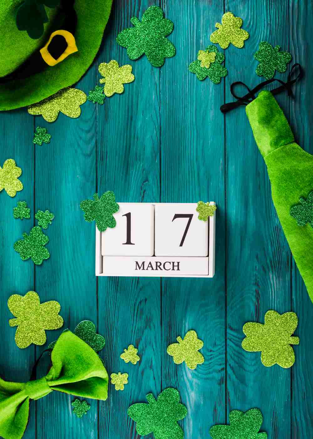 St. Patrick's Day props March 17 blocks, glittery shamrocks and a green hat on a table to celebrate the date of St. Patrick's Day.
