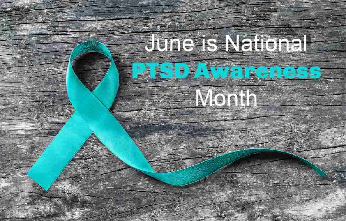 Teal ribbon folder on a wood background with words June is National PTSD Awareness Month.