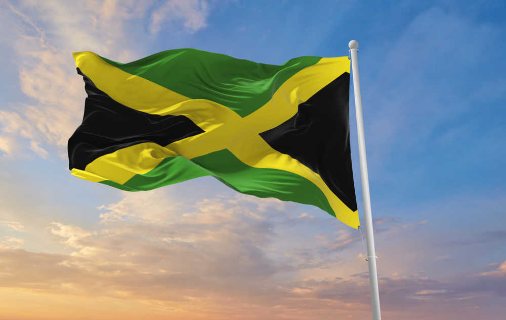 A jamaican flag. A Jamaican flag waving in the wind in front of a a sunset.