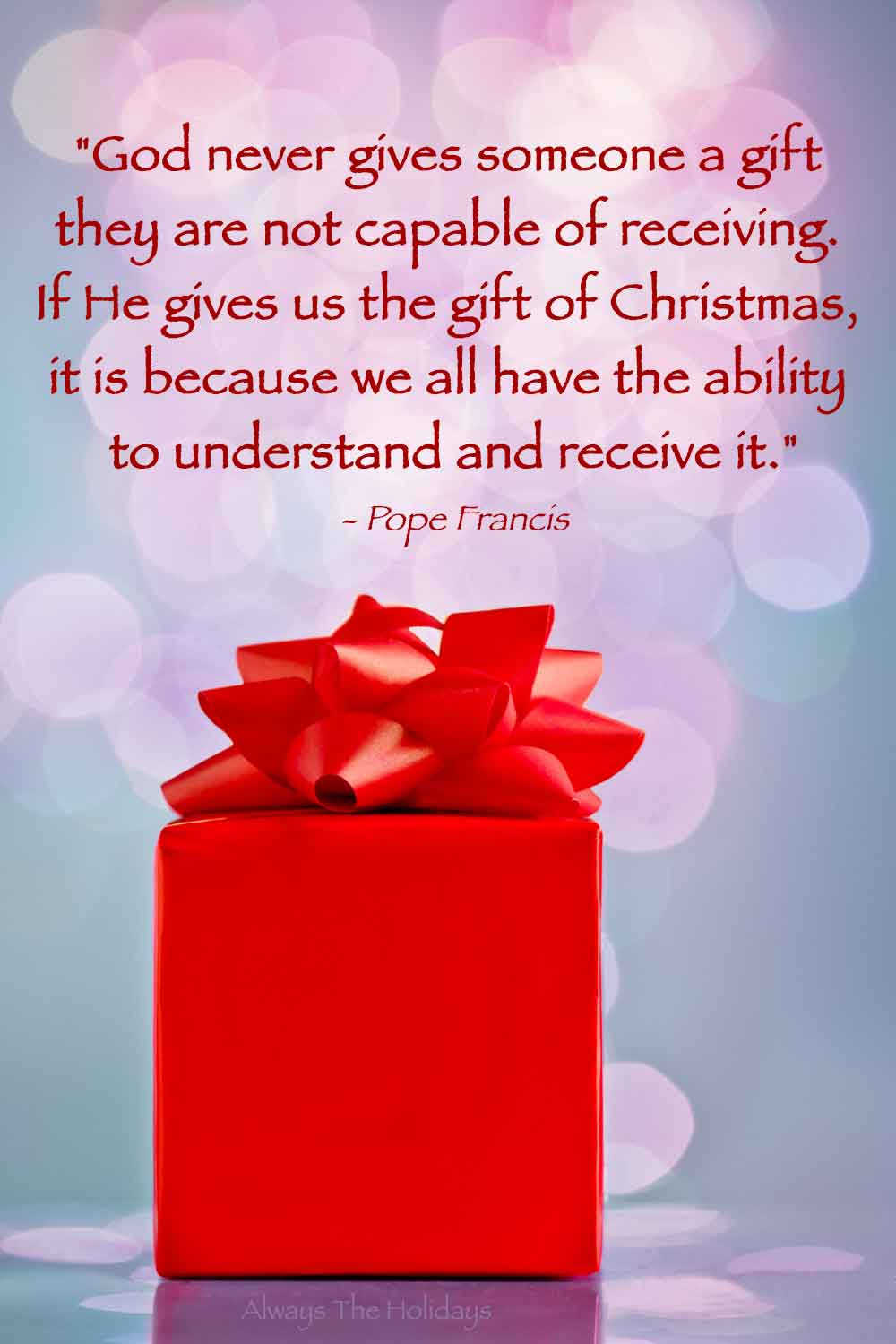 A red Christmas present in front of a pink bokeh with a text overlay containing a religious Christmas quotes about God on it.