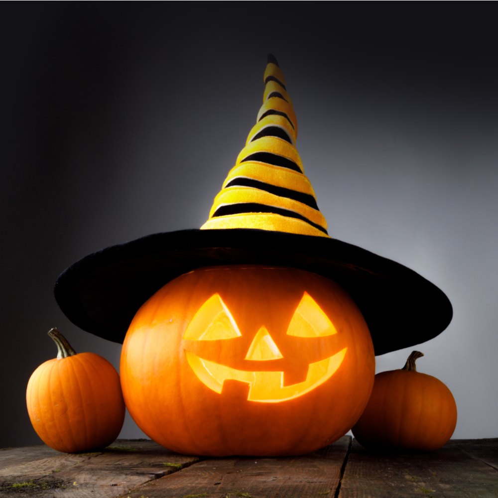 Jack o lantern with witch hat. Happy pumpkin faces carved on a pumpkin wearing a yellow and black striped witch hat.
