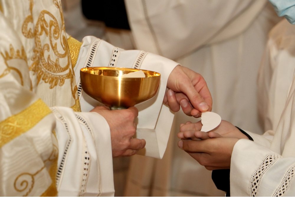 A Catholic priest offering a person Eucharist during Mass on All Saints' Day.