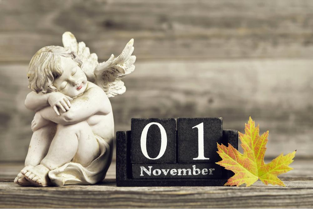 Black blocks that read "November 1" in between an angel statue and a yellow leaf.