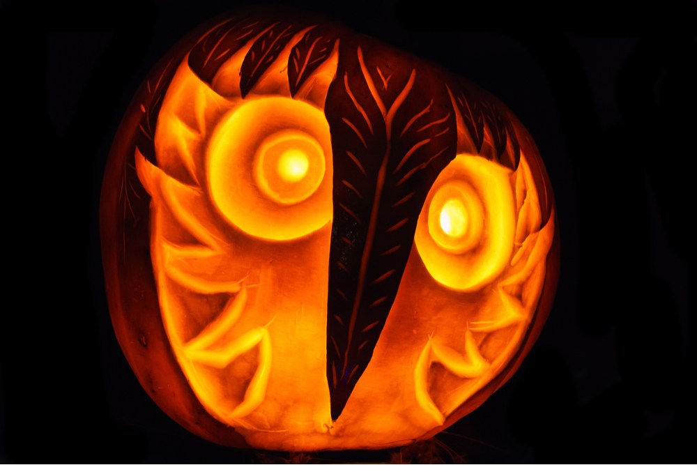 Owl pumpkin. An owl pumpkin carving lit up in darkness.