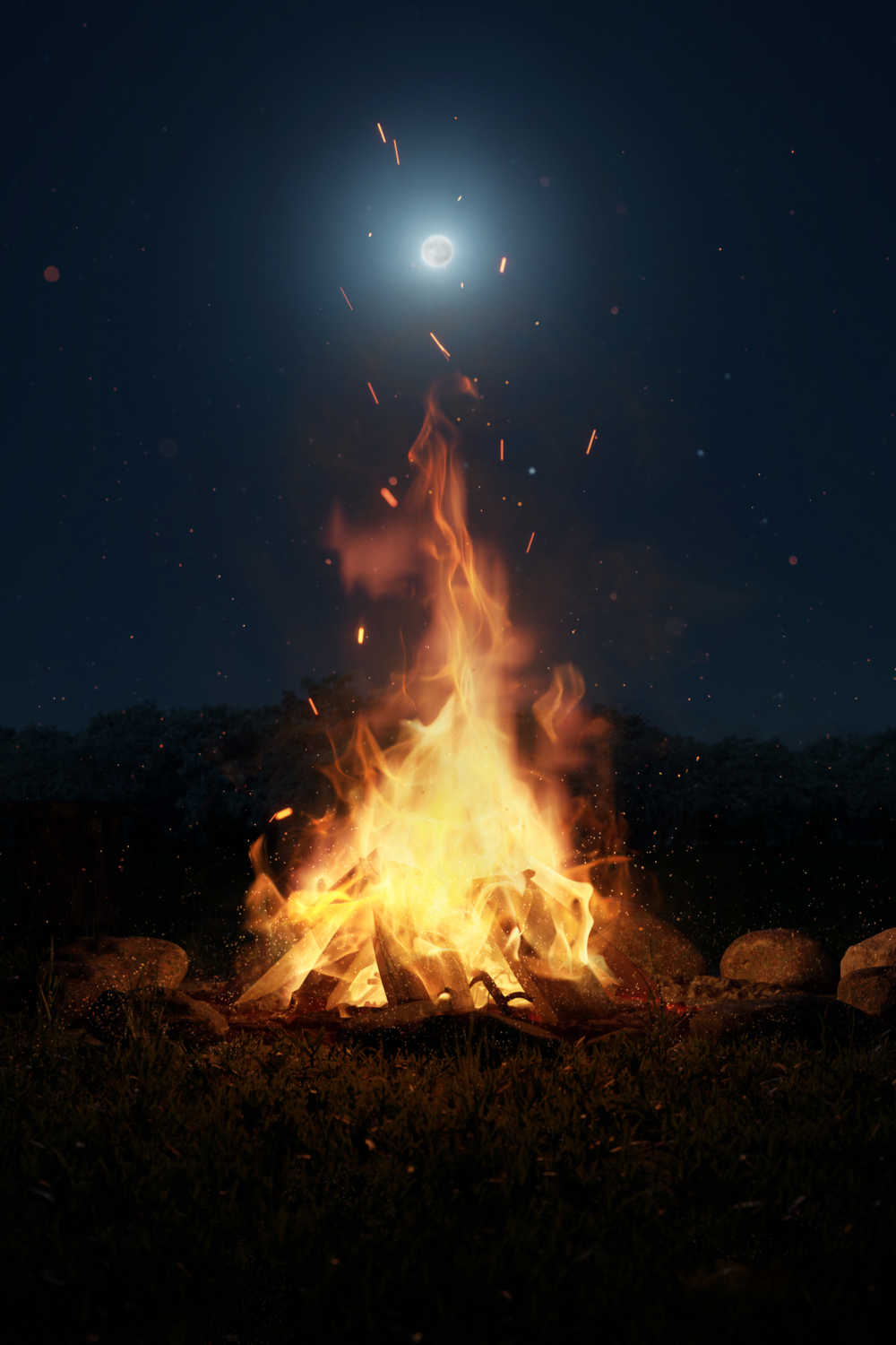 Large bonfire under the moon. A large bonfire in an empty field at night under the moon to honor a Samhain tradition.