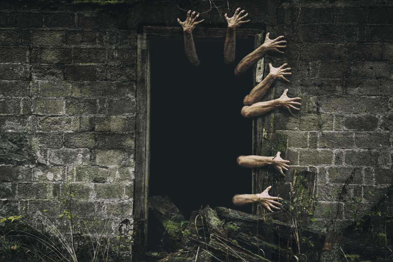 Hands reaching out of dark doorway. Seven hands reaching out of a dark doorway onto a brick wall to represent Samhain monsters.