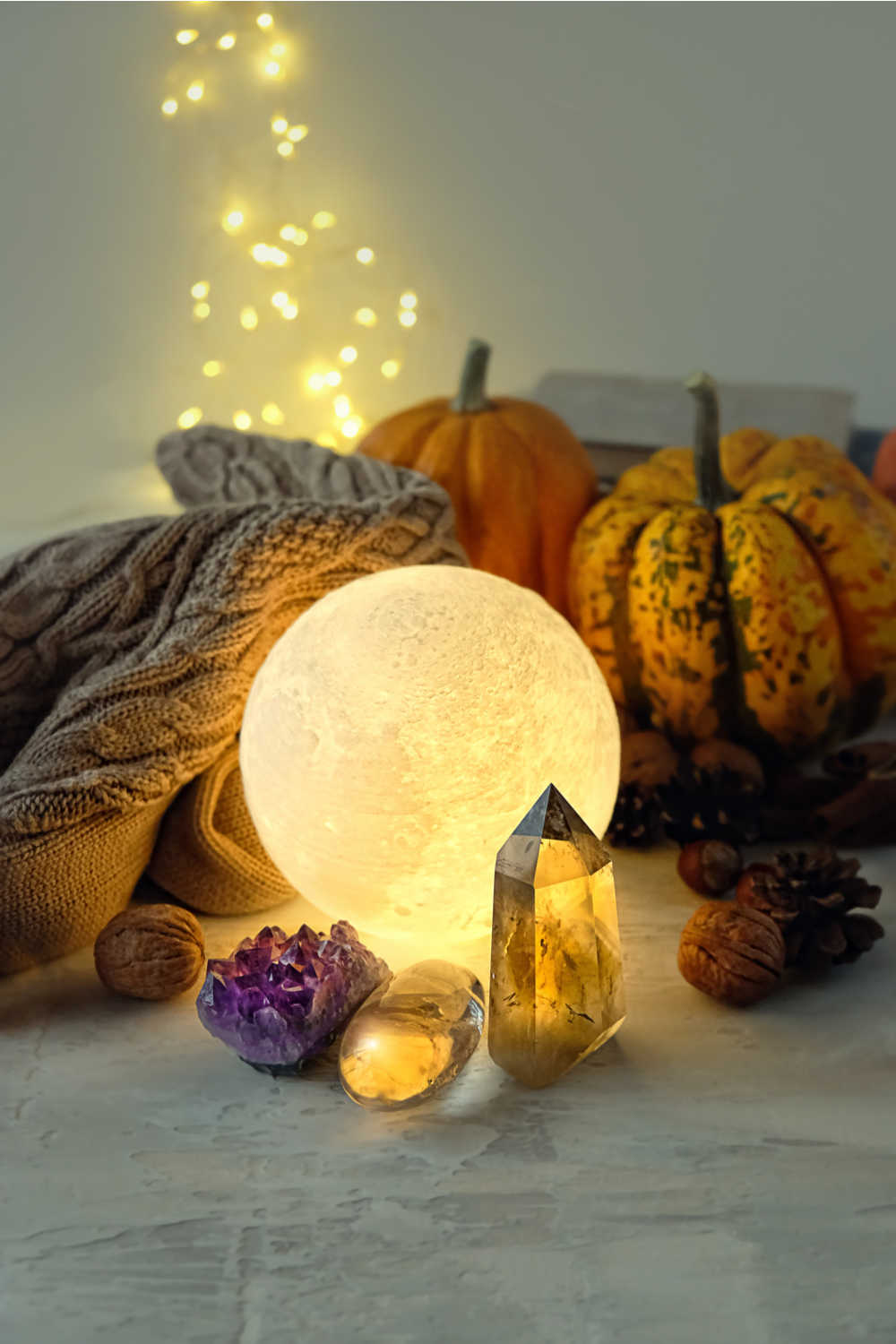 Moon globe, crystals, nuts, pumpkins, and blanket. A moon globe, crystals, pumpkins, nuts, a blanket and twinkle lights that emphasize the meaning of Samhain.
