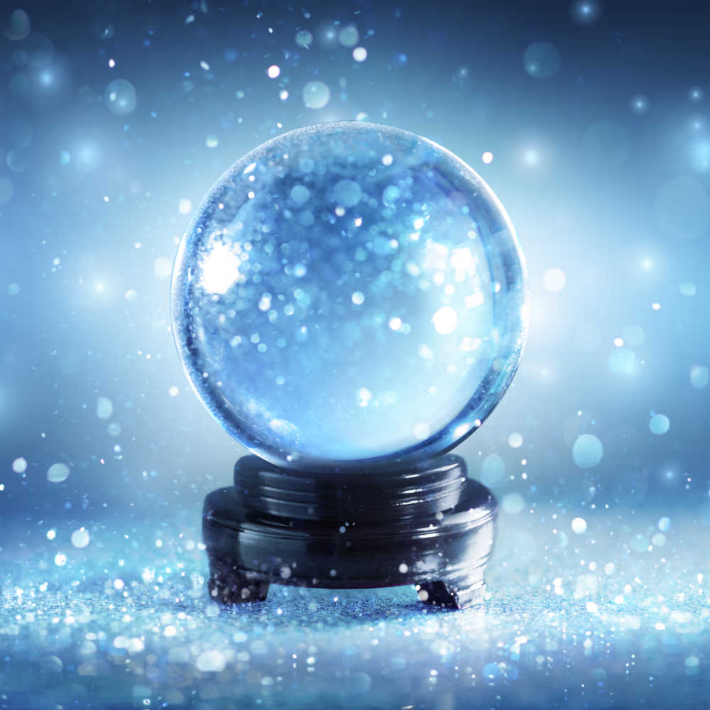 Divination globe. A crystal ball with snow falling around it in a blue hue to symbolize divination during the festival of Samhain.