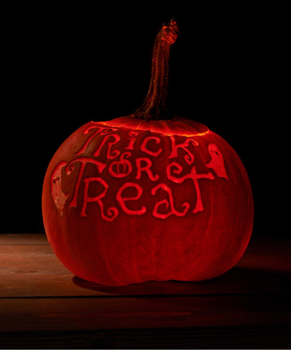 Trick or treat pumpkin. A trick or treat pumpkin carving on a pumpkin on a wooden table.