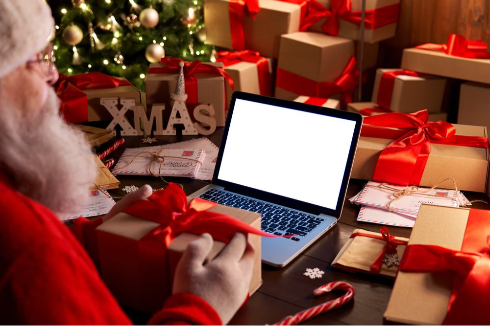 Santa at his computer. Santa in his workshop at his desk with his computer open responding to emails, which answers the question "does Santa have an email address?".