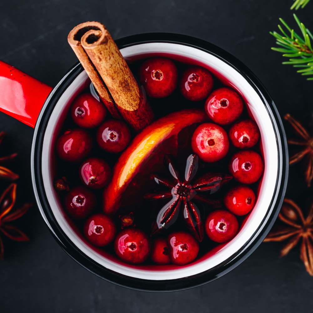 Mulled wine with cranberries. A mug of spiced wine with cranberries, star anise, oranges, and cinnamon as an example of how to eat cranberries.