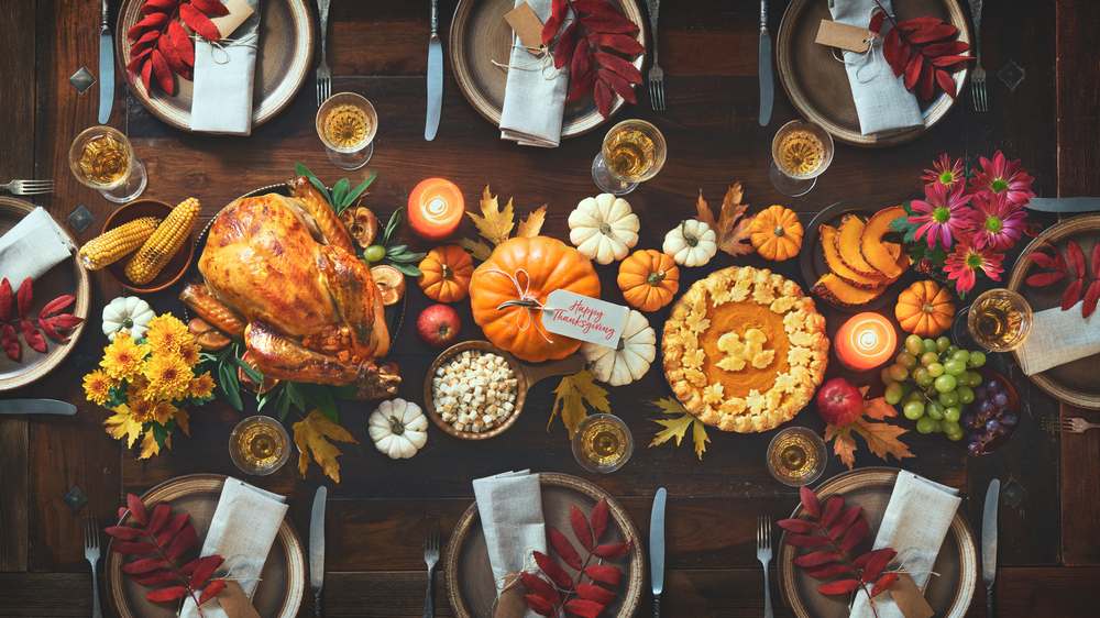 Thanksgiving table set for eight people. A Thanksgiving table set for eight people, with all of the symbols of Thanksgiving present on the table, pumpkins, leaves, turkey, etc.