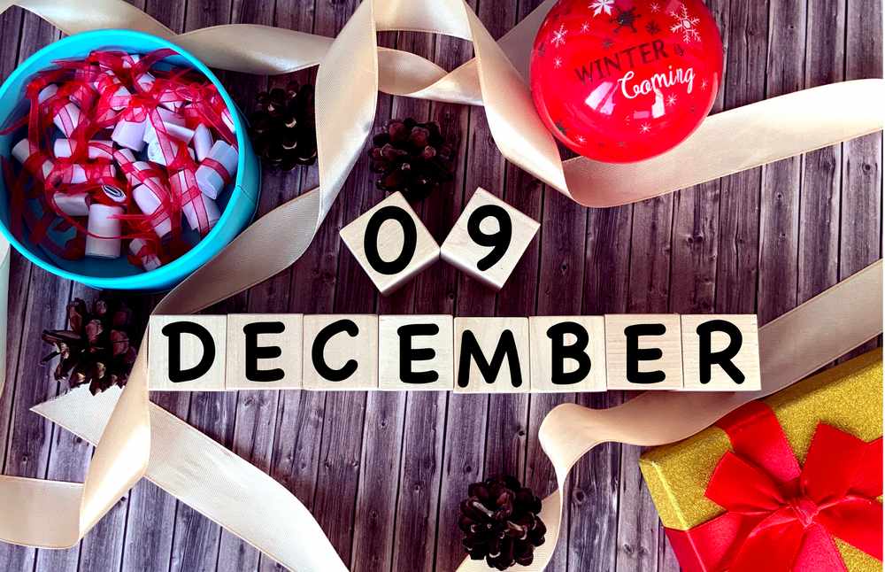 Blocks that read December 9 surrounded by a ribbon, with a present, an ornament, and a bowl of tiny Christmas notes.