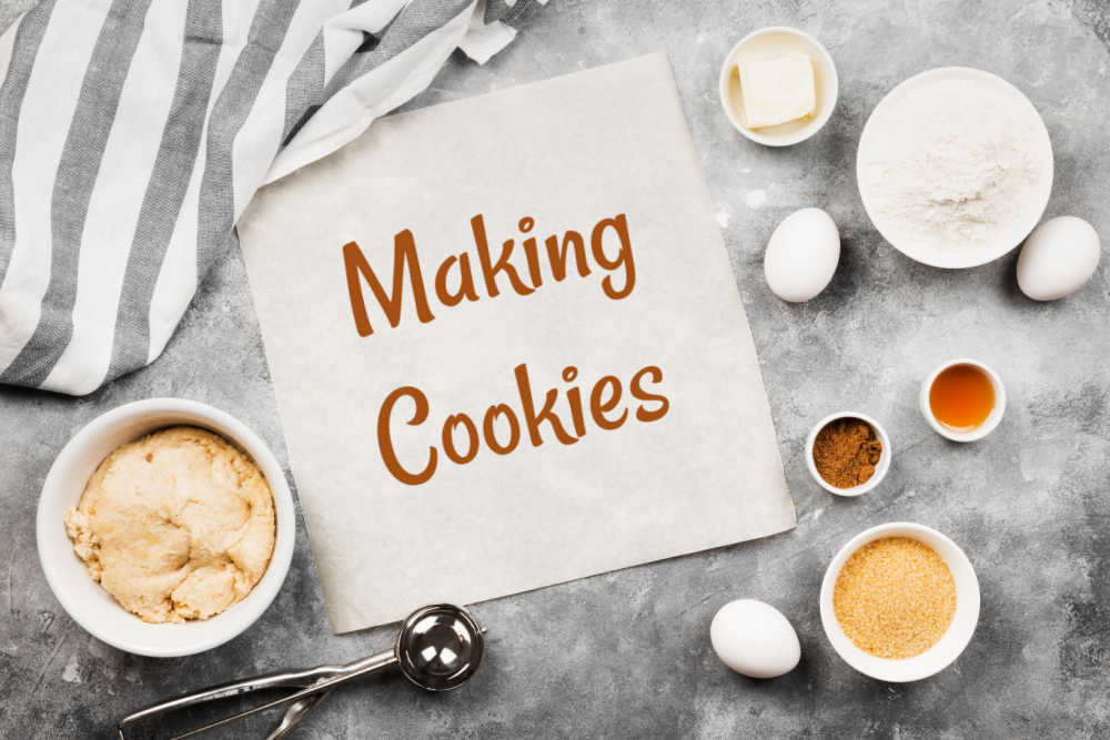Ingredients for cookies and words Making Cookies on a white mat.