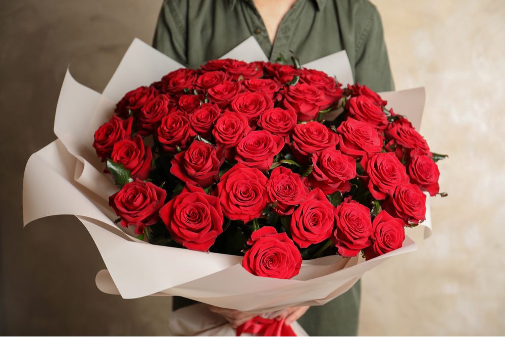 Bouquet of red roses A woman in a green shirt holding an enormous bouquet of red roses to celebrate Rose Day.