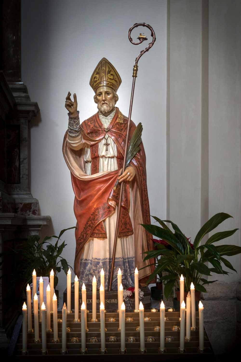 St Valentine statue A statue of St Valentine in a church with lots of taper candles at the foot of the statue.