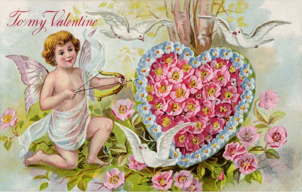 One of the first Valentines depicting a cupid holding a bow and arrow pointing towards a heart made of flowers, in a woodland setting with doves flying above and text that reads "to my Valentines".