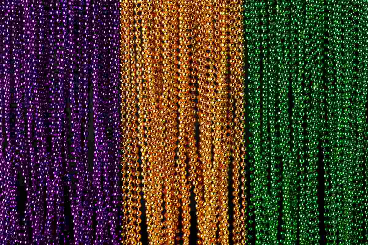 Beads in Mardi Gras colors Mardi Gras beads in the colors purple, gold and green lined up next to each other to symbolize the colors of Mardi Gras.