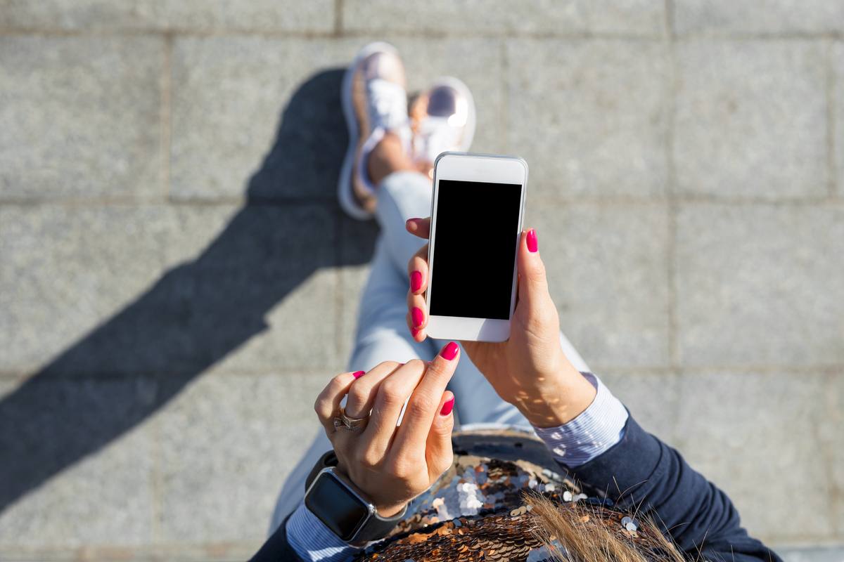 Person holding iPhone A woman with red painted nails holding an iPhone getting ready to turn it on.