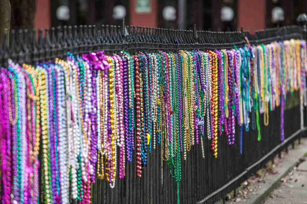 Mardi Gras beads on fence A wrought iron fence lined with dozens of plastic Mardi Gras beads.
