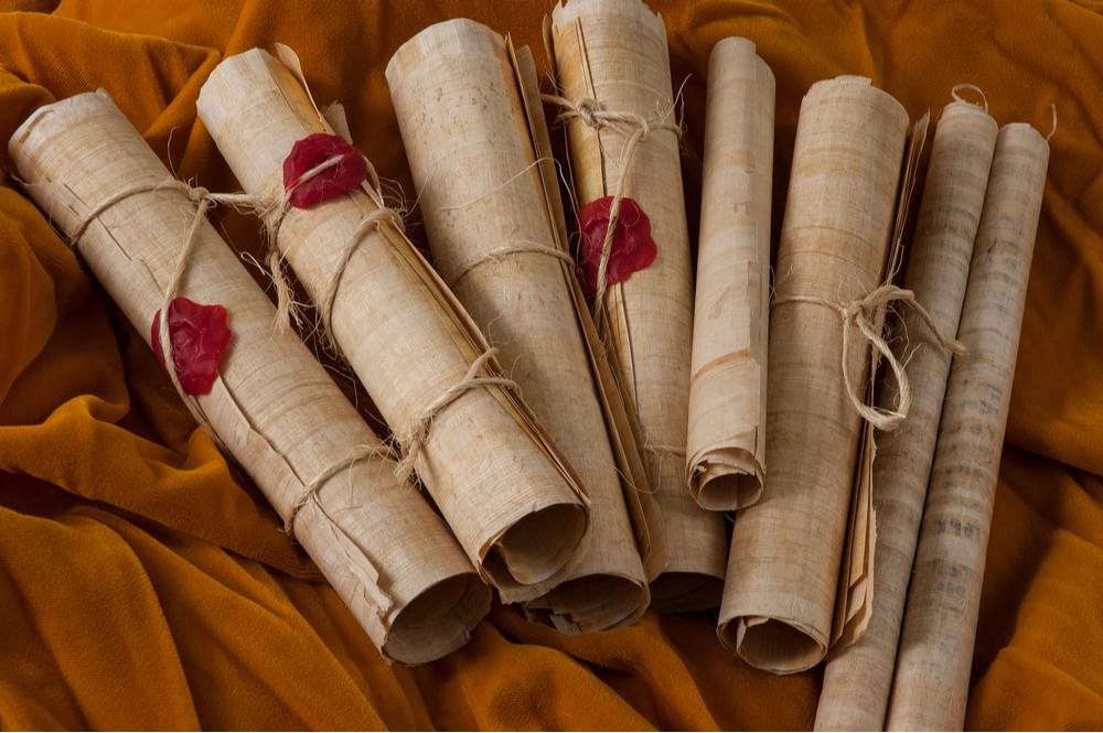Multiple scrolls of parchment Several scrolls rolled up and tied with twine containing information about history and mythology.